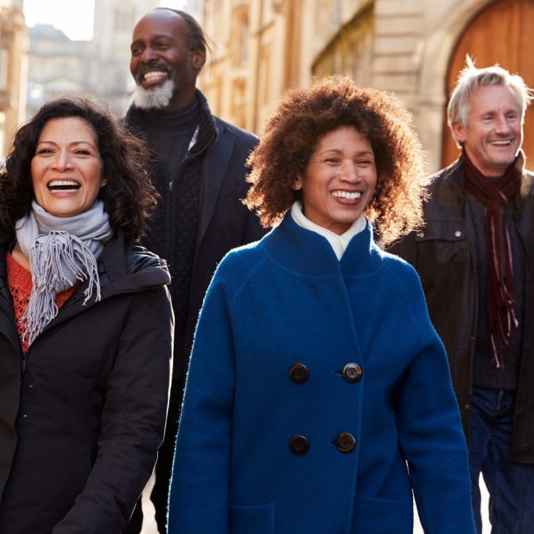 Vier lächelnde Personen gehen durch die Altstadt.