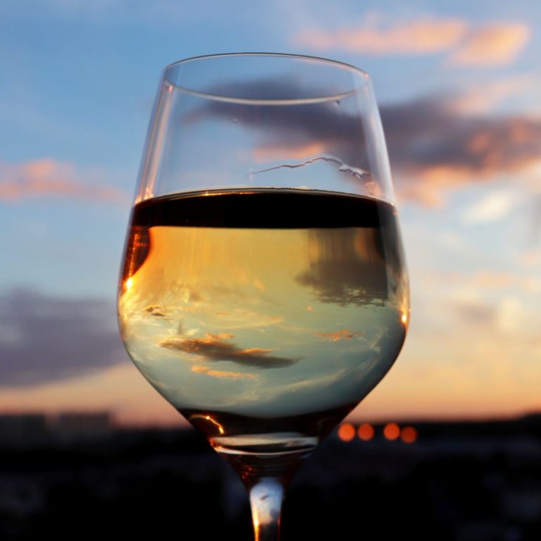 Ein Glas Weißwein im Abendlicht.