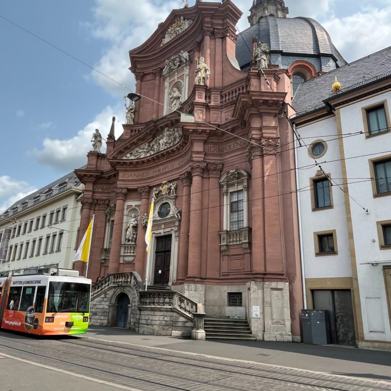 Barocke Fassade der Neumünsterkirche mit Straßenbahn im Vordergrund.